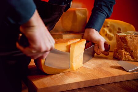Cut with a knife piece of cheese on a dark table.の写真素材