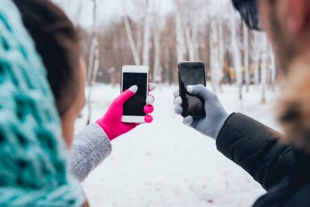 Couple using smartphone in winter with gloves for touch screens. Backgoundの写真素材