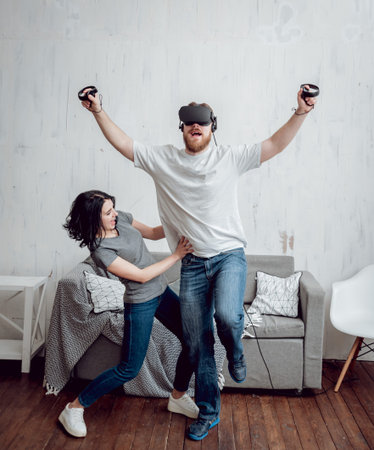 The young man with girlfriend playing games with virtual reality goggles