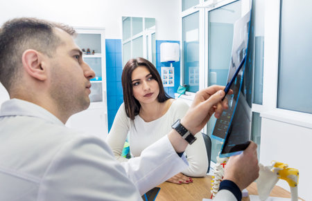 Traumatologist showing MRI film to patient in hospital.