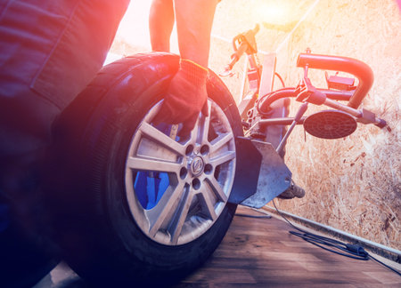 Professional car mechanic replace tire on wheel.