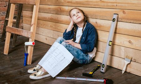 Little girl in a room with a wooden wall. Constructionの写真素材