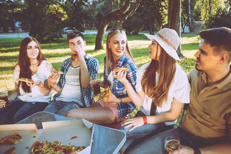 Cheerful friends on picnic in the park. Eating pizzaの写真素材