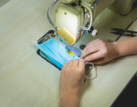 Woman sew the facial medical at sewing machine. Coronavirus pandemia.