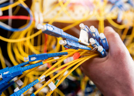 Network engineer working in server room. Connecting network cables to switchesの写真素材