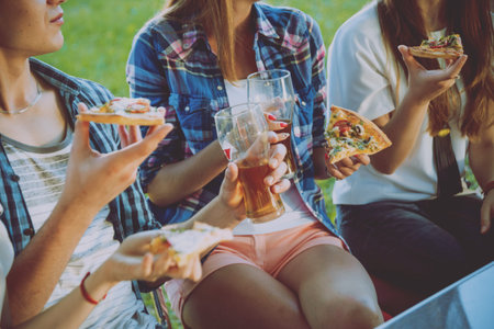 Cheerful friends on picnic in the park. Eating pizza.の写真素材
