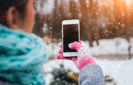 Woman using smartphone in winter with gloves for touch screens. Backgoundの写真素材