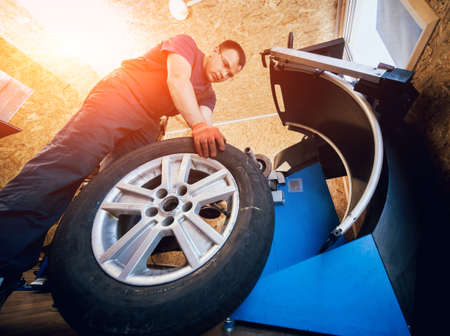 Professional car mechanic replace tire on wheel.の写真素材