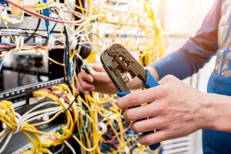 Network engineer working in server room. Connecting network cables to switches. Data center