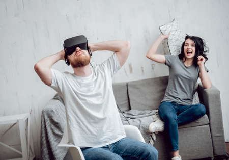 The young man with girlfriend playing games with virtual reality gogglesの写真素材
