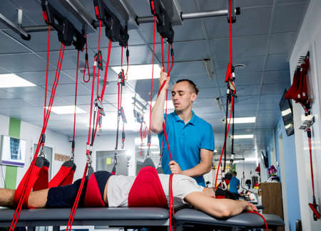 Physiotherapy. Suspension training therapy. Young man doing fitness therapyの写真素材