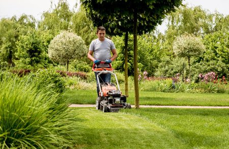 Gardener mowing the lawn. Landscape design. Green grass background