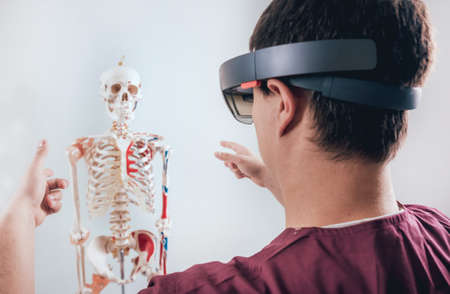 Doctor uses augmented reality goggles to exam human skeleton.の写真素材