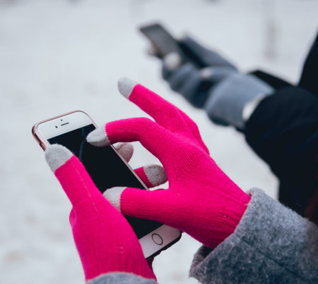 Couple using smartphone in winter with gloves for touch screens