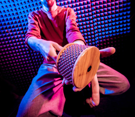 Young man playing on maracas in sound recording studio.