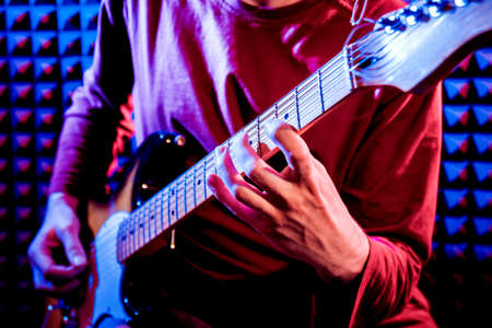 Young man playing on the guitar in sound recording studio.の写真素材