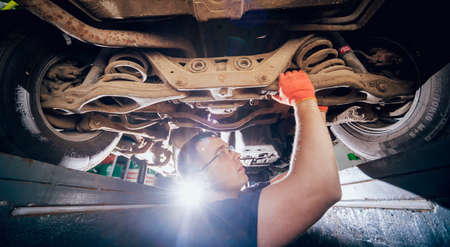 Car mechanic repair car suspension of lifted automobileの写真素材