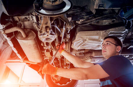 Car mechanic repair car suspension of lifted automobileの写真素材
