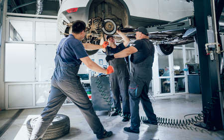 Car mechanics repair car suspension of lifted automobileの写真素材