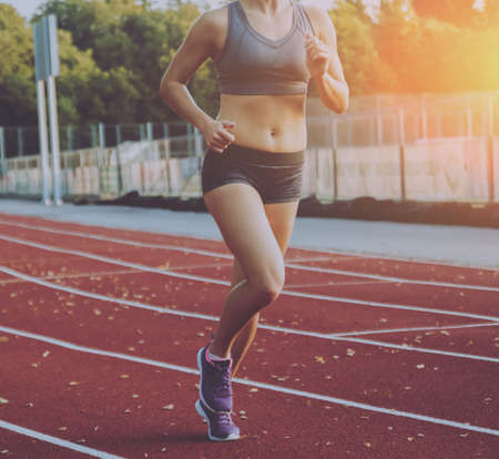 A female athlete runs along the treadmill.の写真素材