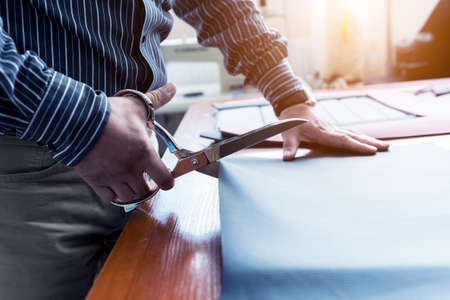 Designer tailor sew seat covers. Man use scissors for his work.の写真素材