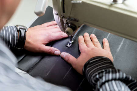 Designer tailor sew seat covers. Man use sewing machine for his work.の写真素材