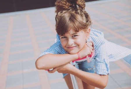Little girl riding scooter outdoors. Street urban background.の写真素材