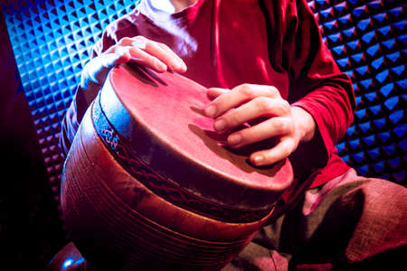Young man playing on djembe in sound recording studio.の写真素材