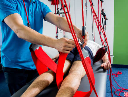 Physiotherapy. Suspension training therapy. Young man doing fitness therapyの写真素材