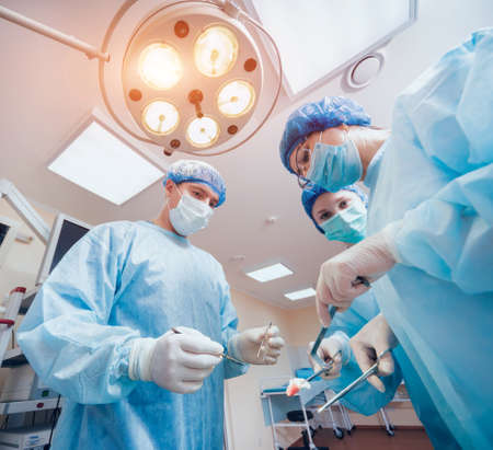 Group of surgeons in operating room with surgery equipment.の写真素材