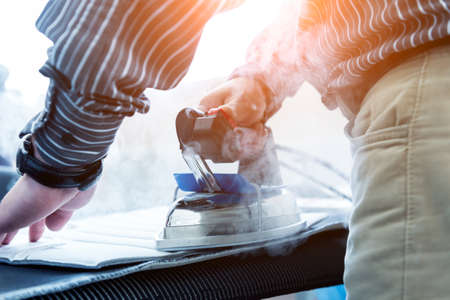Designer tailor sew seat covers. Man use iron for his work.の写真素材