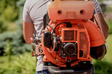 Gardener in protective mask and glasses spraying toxic pesticides treesの写真素材