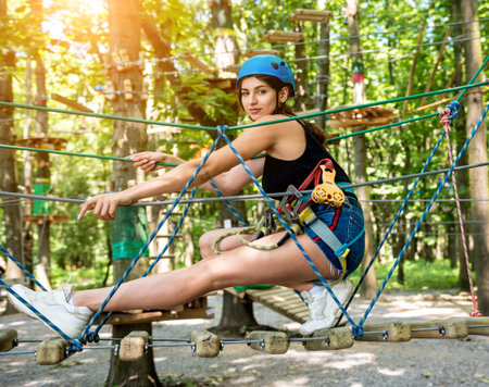 Young woman in adventure rope park. Climbing Equipment.