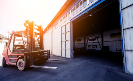 The big industrial forklift drives into the warehouse.