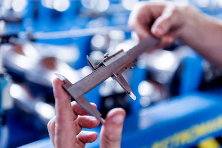 Male hands hold vernier caliper and measure steel collar.の写真素材