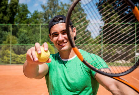 Portrait of young athletic man on tennis court.の写真素材