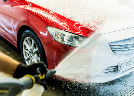 Worker washing car with active foam on a car wash.の写真素材