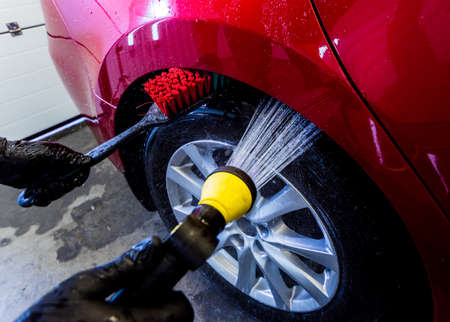 Cleaning the car wheel with a brush and waterの写真素材
