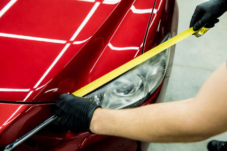 Car service worker applying protective tape on the car details before polishing.の写真素材