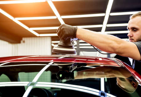 Car service worker polishes a car details with orbital polisher.の写真素材