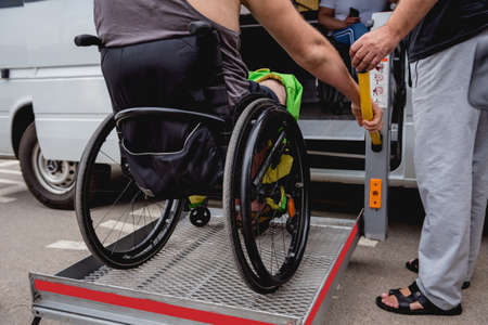 Disabled man on wheelchair using accessible vehicle with lift mechanism.の写真素材