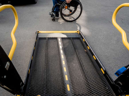 A man in a wheelchair moves to the lift of a specialized vehicleの写真素材