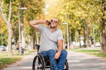Handicapped man in wheelchair at the park alley use a smartphoneの写真素材