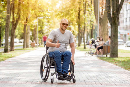 Handicapped man in wheelchair walk at the park alleyの写真素材