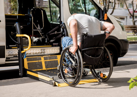 A man in a wheelchair moves to the lift of a specialized vehicle