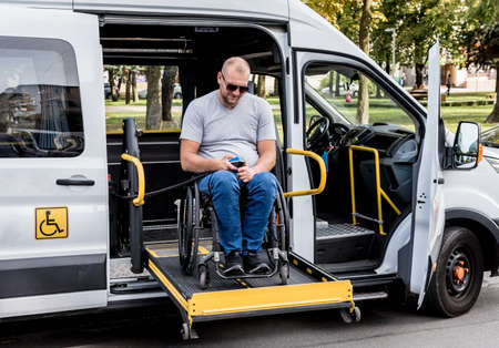A man in a wheelchair on a lift of a vehicle for people with disabilitiesの写真素材