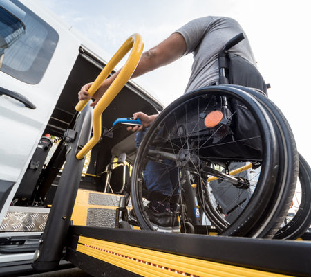 A man in a wheelchair on a lift of a vehicle for people with disabilities