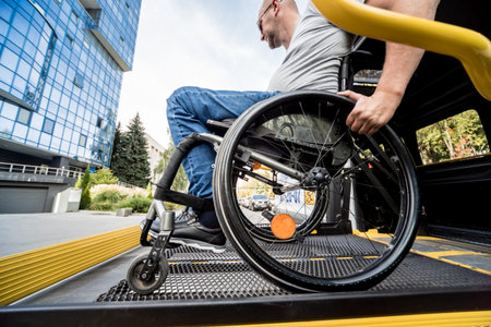 A man in a wheelchair on a lift of a vehicle for people with disabilities