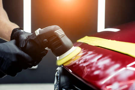 Car service worker polishes a car details with orbital polisher.の写真素材