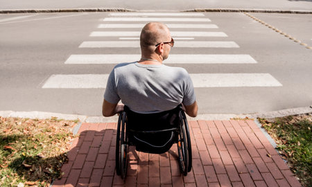 Handicapped man in wheelchair preparing to cross the road on pedestrian crossing